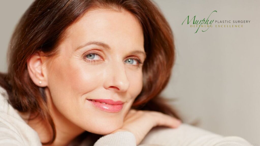 Woman with brown hair and blue eyes is smiling (MODEL) Murphy Plastic Surgery: Terrence Murphy, MD Logo